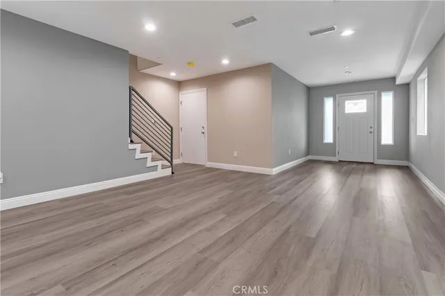 a view of an empty room with wooden floor and stairs