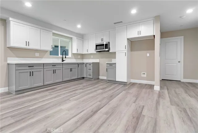 a large kitchen with kitchen island white cabinets and stainless steel appliances