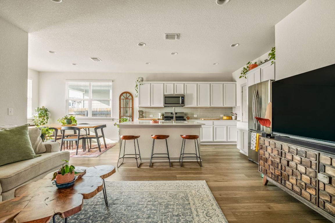 Living area with a textured ceiling, light wood-type flooring, and recessed lighting