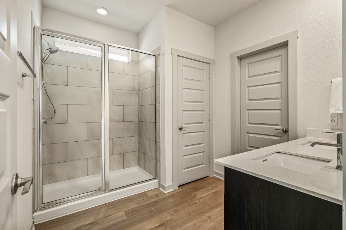 10002 Baden Lane Austin, TX 78754 - Photo 16 of 28 Full bath with double vanity, a stall shower, and light wood finished floors