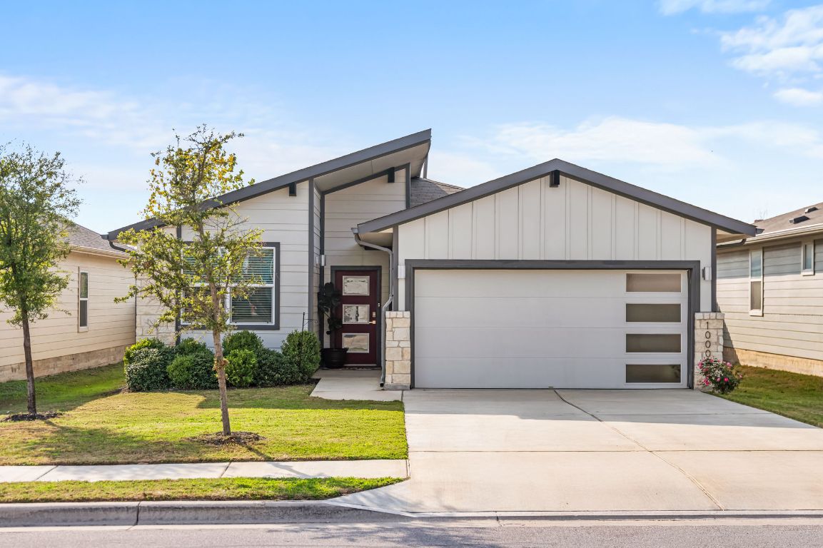 10002 Baden Lane Austin, TX 78754 - Photo 2 of 28 View of front facade featuring board and batten siding, a front yard, a garage, concrete driveway, and stone siding