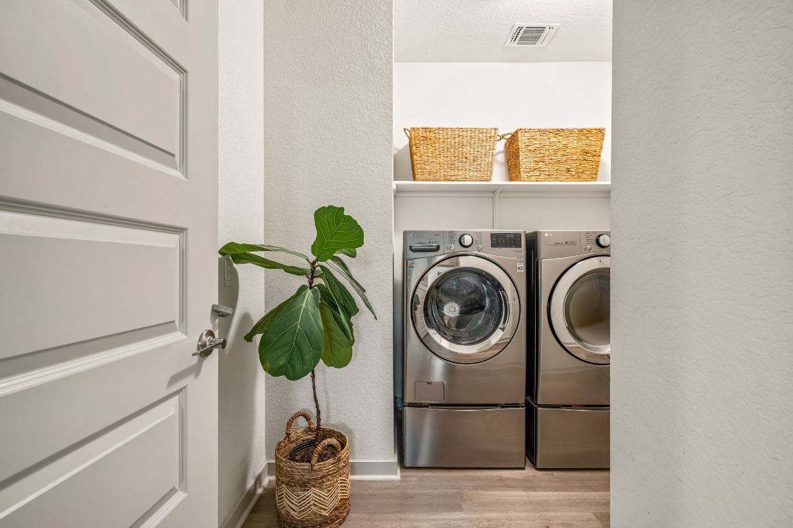 10002 Baden Lane Austin, TX 78754 - Photo 22 of 28 Laundry room with a textured wall, light wood-type flooring, washing machine and clothes dryer, and a textured ceiling