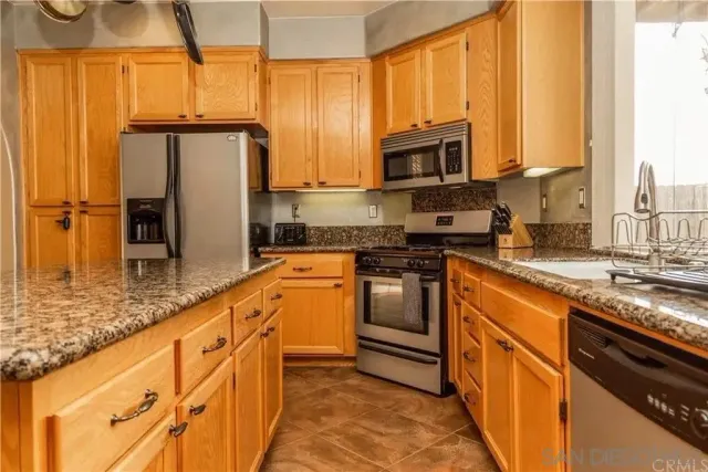 a kitchen with stainless steel appliances granite countertop a refrigerator a stove and a sink with wooden floor