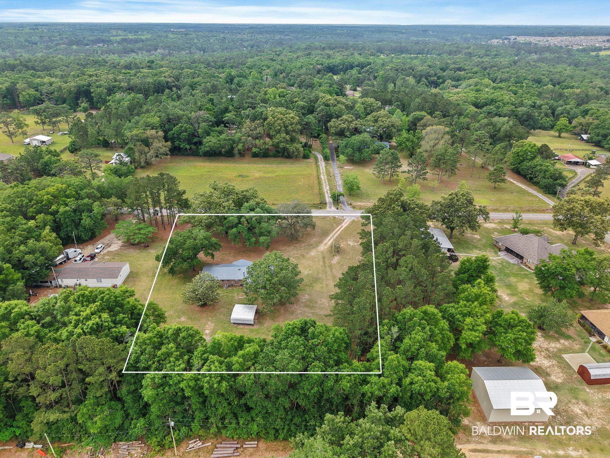 13653 Roberts Road Loxley, AL 36551 - Photo 32 of 33 Expansive property featuring a single-story residence with a light-colored roof, surrounded by mature trees
