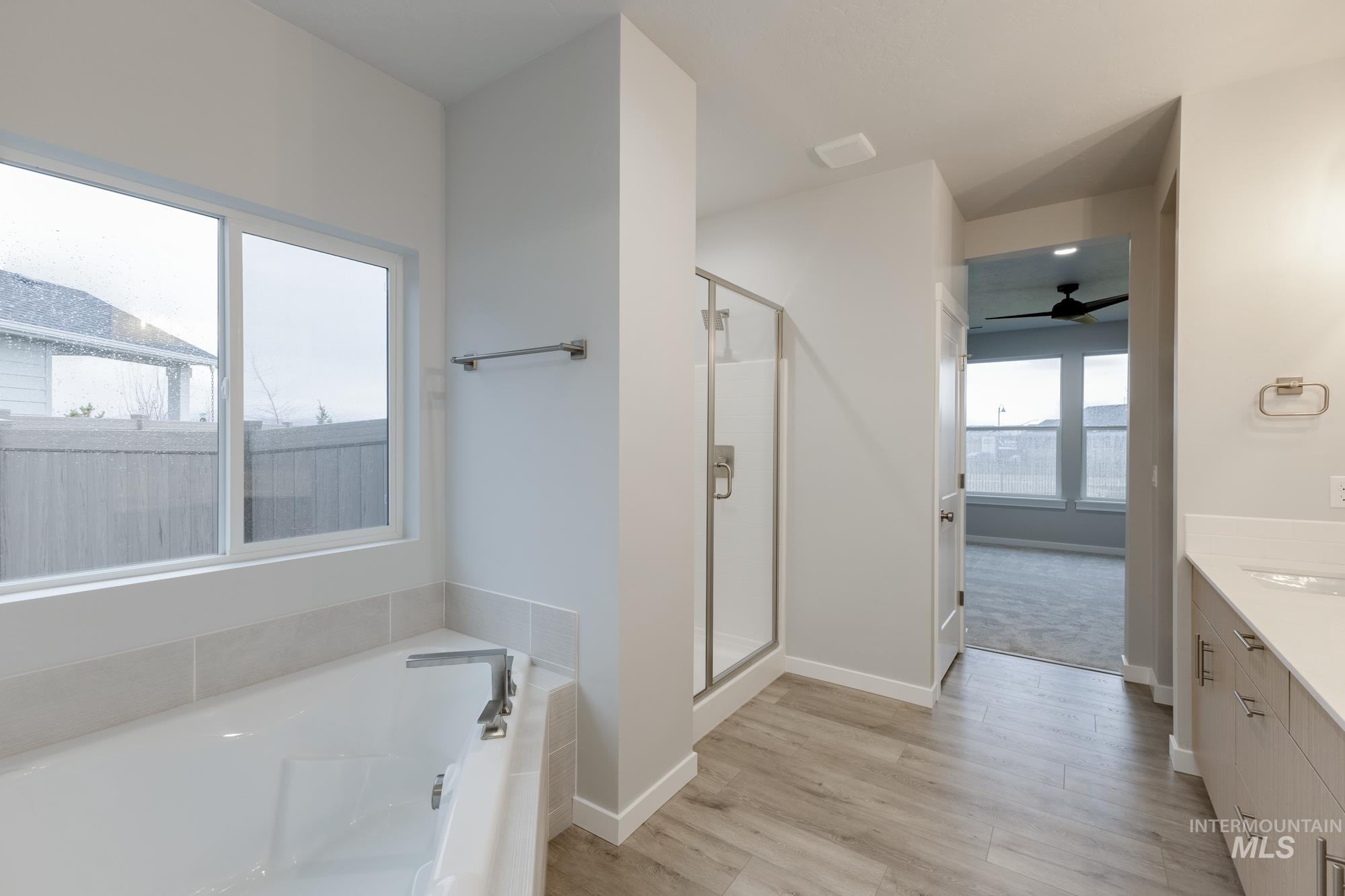 6558 South Sunfish Avenue Boise, ID 83709 - Photo 17 of 32 Full bath with vanity, a ceiling fan, light wood-type flooring, a shower stall, and a bath