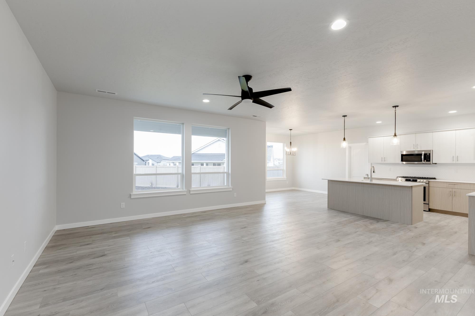6558 South Sunfish Avenue Boise, ID 83709 - Photo 9 of 32 Unfurnished living room with a ceiling fan, recessed lighting, light wood-type flooring, and a chandelier