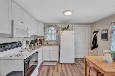 a kitchen with a sink a refrigerator and white cabinets
