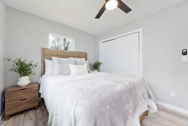 a bedroom with a large bed and a chandelier fan