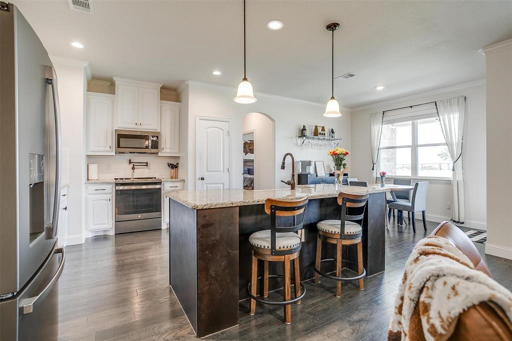 340 Sanger Drive Springtown, TX 76082 - Photo 11 of 38 a kitchen with stainless steel appliances granite countertop a stove a sink a oven a dining table and chairs with wooden floor