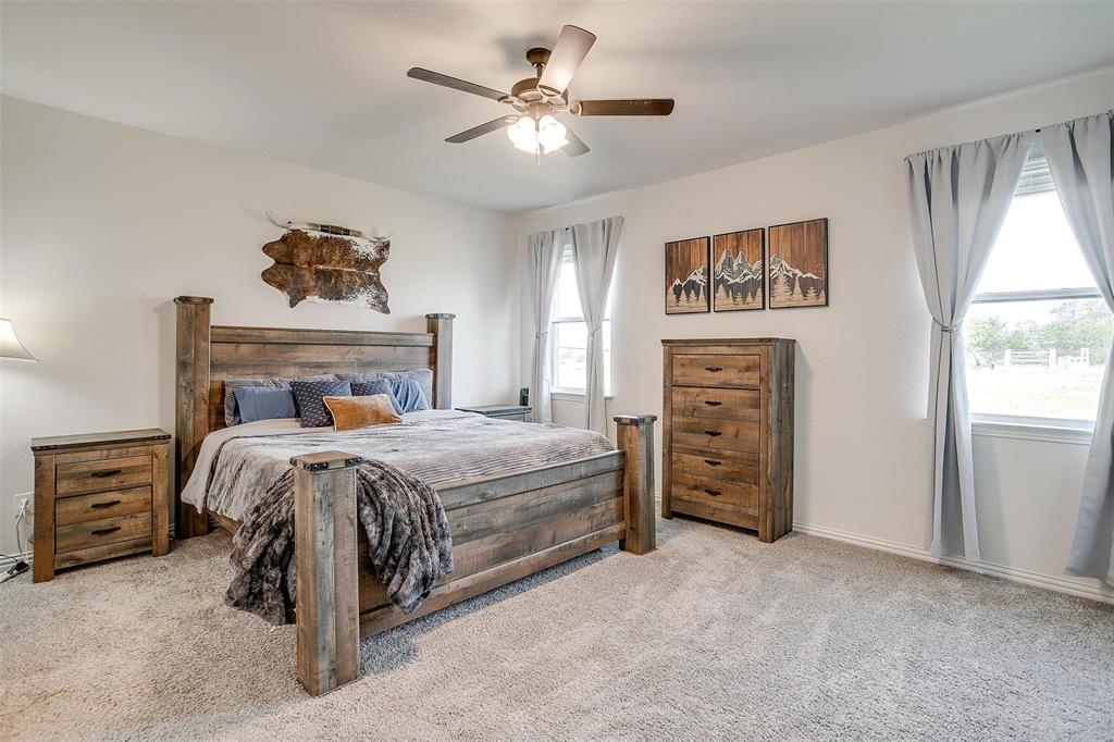 340 Sanger Drive Springtown, TX 76082 - Photo 18 of 38 a bedroom with a bed and a chandelier
