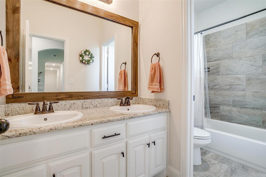 340 Sanger Drive Springtown, TX 76082 - Photo 25 of 38 a bathroom with a granite countertop sink a toilet and a bathtub