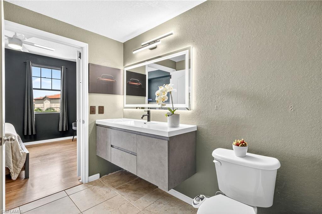 12955 Positano Circle, Unit 305 Naples, FL 34105 - Photo 8 of 10 Half bathroom featuring a textured wall, vanity, and light tile patterned flooring