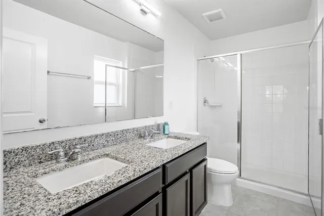 a bathroom with a granite countertop sink a toilet and shower