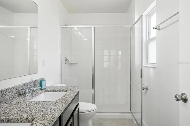 a bathroom with a granite countertop sink toilet and shower