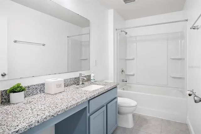 a bathroom with a granite countertop sink toilet a large mirror a bathtub and shower