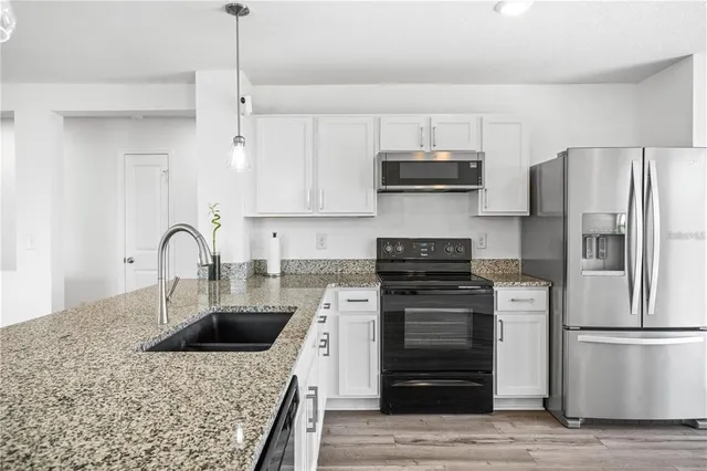 a kitchen with stainless steel appliances granite countertop a kitchen island a stove and a refrigerator