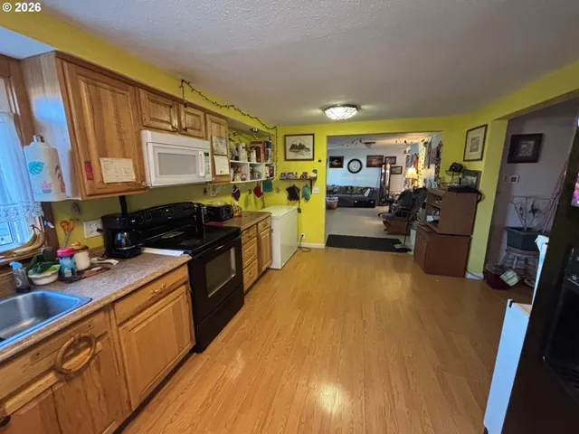 a kitchen with stainless steel appliances a stove top oven a sink dishwasher and wooden cabinets with wooden floor