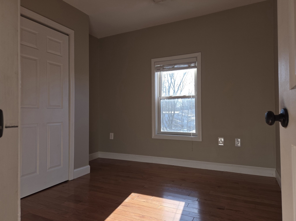 3 Pearl Street, Unit 2 Stoneham, MA 02180 - Photo 17 of 21 an empty room with wooden floor and windows