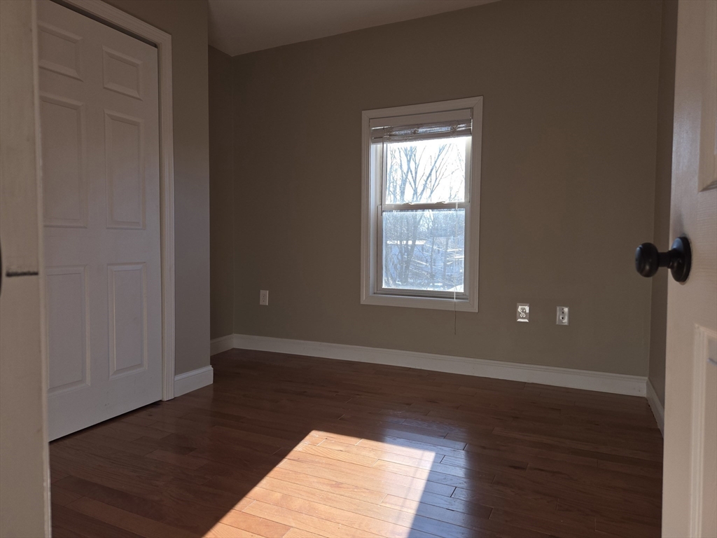 3 Pearl Street, Unit 2 Stoneham, MA 02180 - Photo 18 of 21 an empty room with wooden floor and windows