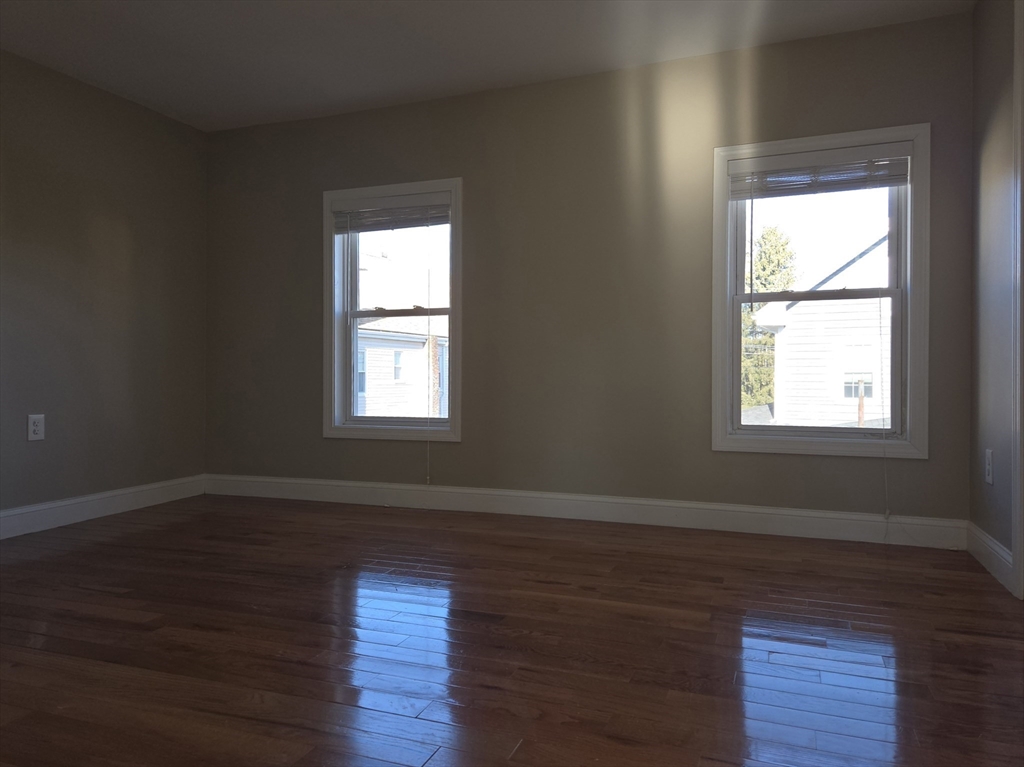 3 Pearl Street, Unit 2 Stoneham, MA 02180 - Photo 20 of 21 an empty room with wooden floor and windows