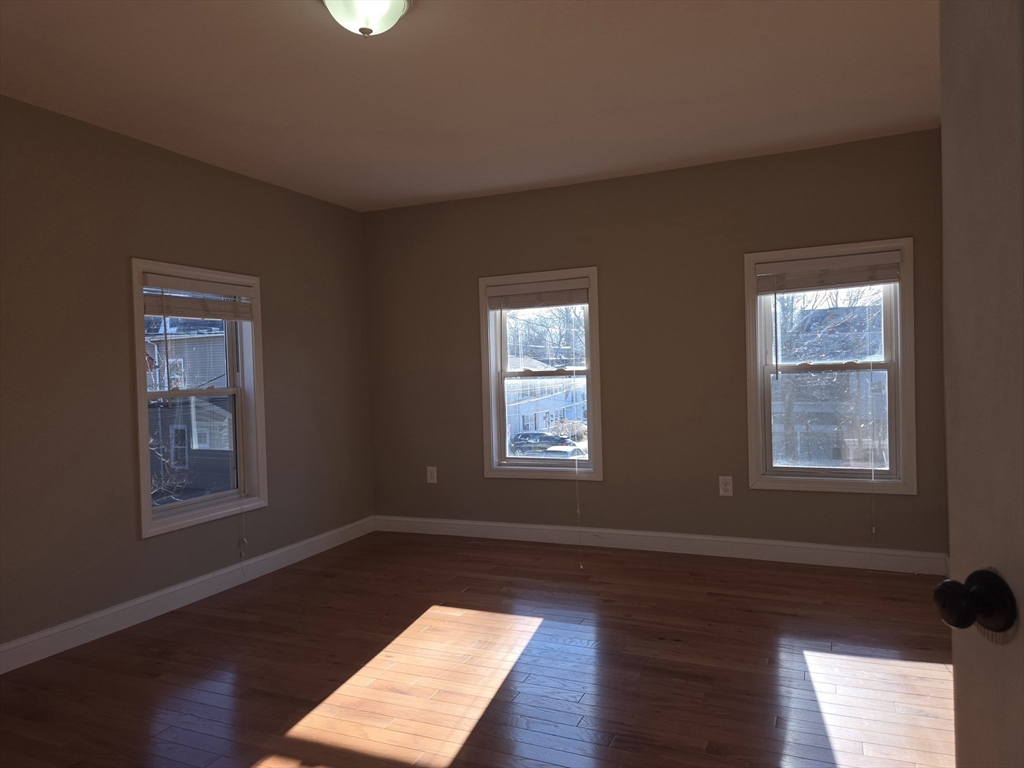 3 Pearl Street, Unit 2 Stoneham, MA 02180 - Photo 21 of 21 a view of an empty room with wooden floor and a window