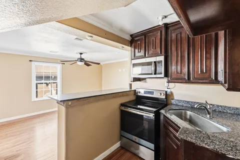 a kitchen that has a sink cabinets counter space and appliances