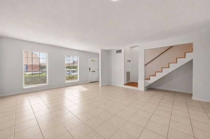 6404 Burgoyne Road, Unit 159 Houston, TX 77057 - Photo 11 of 38 Spacious and bright living area with large windows, tiled floors, and an open staircase, offering a welcoming and versatile space - prior to virtual staging