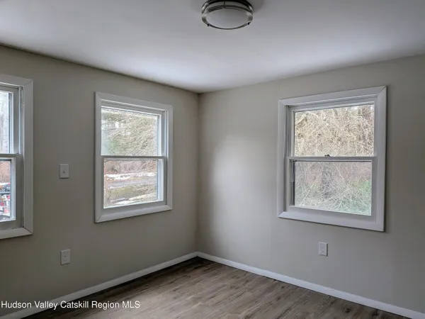 a view of an empty room with a window and wooden floor