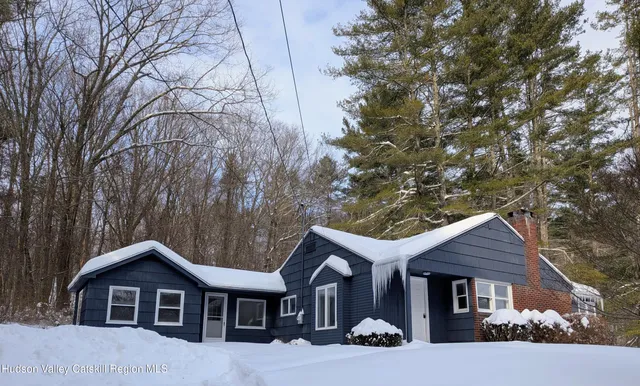 a front view of a house with yard and trees in the background