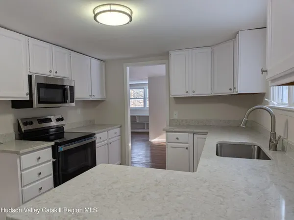 a kitchen with stainless steel appliances granite countertop a refrigerator a stove top oven a sink and dishwasher with wooden floor