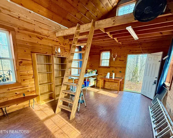 a view of an empty room with wooden floor and windows