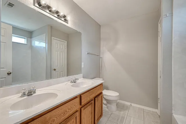 a bathroom with a granite countertop sink a toilet and a mirror