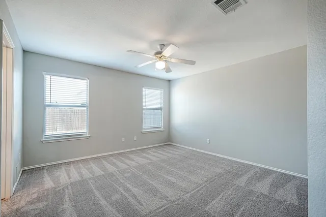 an empty room with windows and a ceiling fan