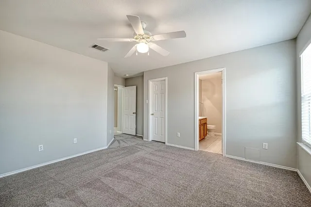 a view of an empty room with a chandelier fan
