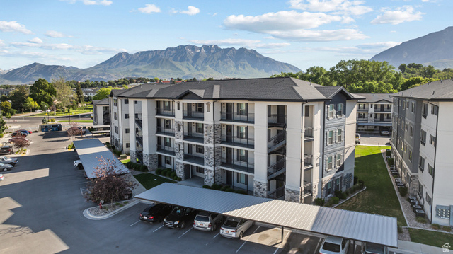 1700 South Sandhill Road West, Unit E 301 Orem, UT 84058 - Photo 20 of 20 Modern apartment building featuring a multi-tone facade with stone accents, individual balconies, dark-pitched roofs, and covered parking structures