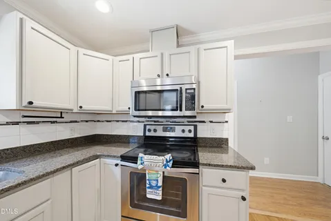 a kitchen with granite countertop a stove sink and microwave