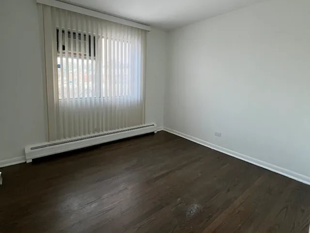 an empty room with wooden floor and windows with curtains