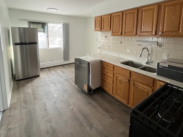 a kitchen with stainless steel appliances granite countertop a refrigerator stove and sink with wooden floor
