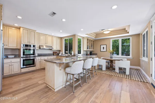 a large open kitchen with a refrigerator a stove a sink a dining table and chairs