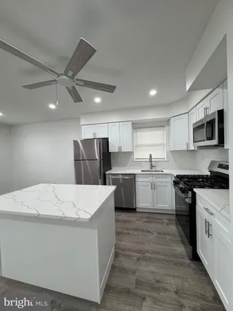 a large kitchen with stainless steel appliances kitchen island a stove a sink a refrigerator a microwave oven with cabinets and wooden floor