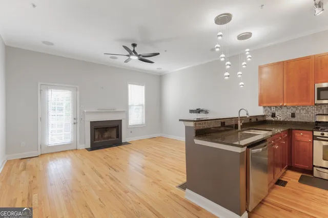 a kitchen with granite countertop a stove top oven a sink dishwasher and a fireplace with wooden floor