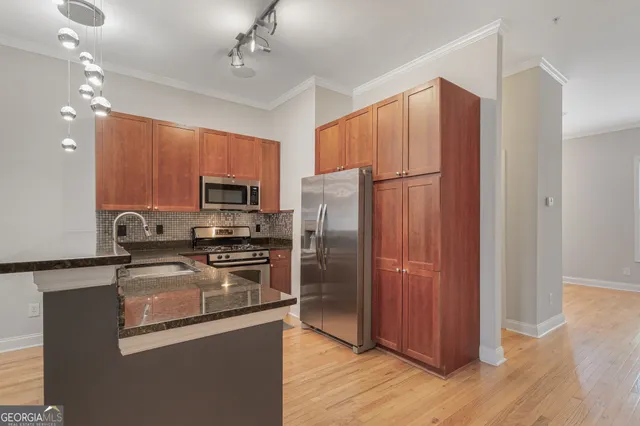 a kitchen with granite countertop stainless steel appliances a refrigerator cabinets and wooden floor