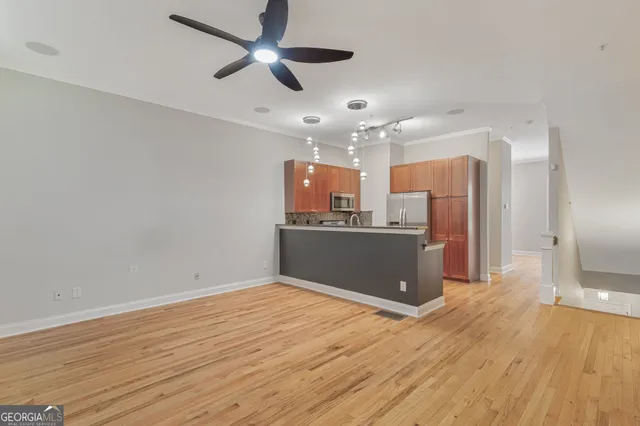 a view of kitchen and empty room with wooden floor