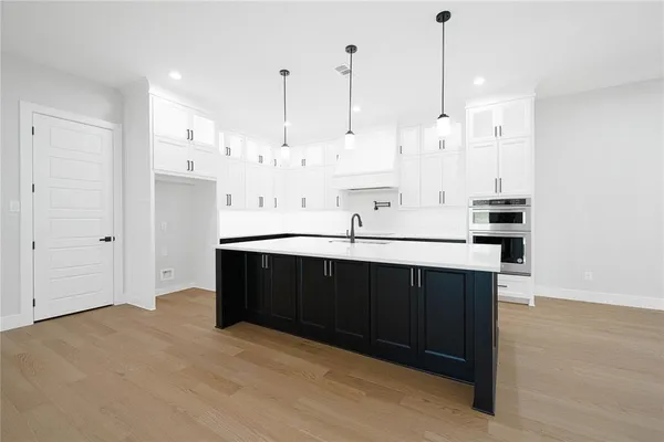 a view of kitchen with stainless steel appliances kitchen island sink refrigerator and wooden floor