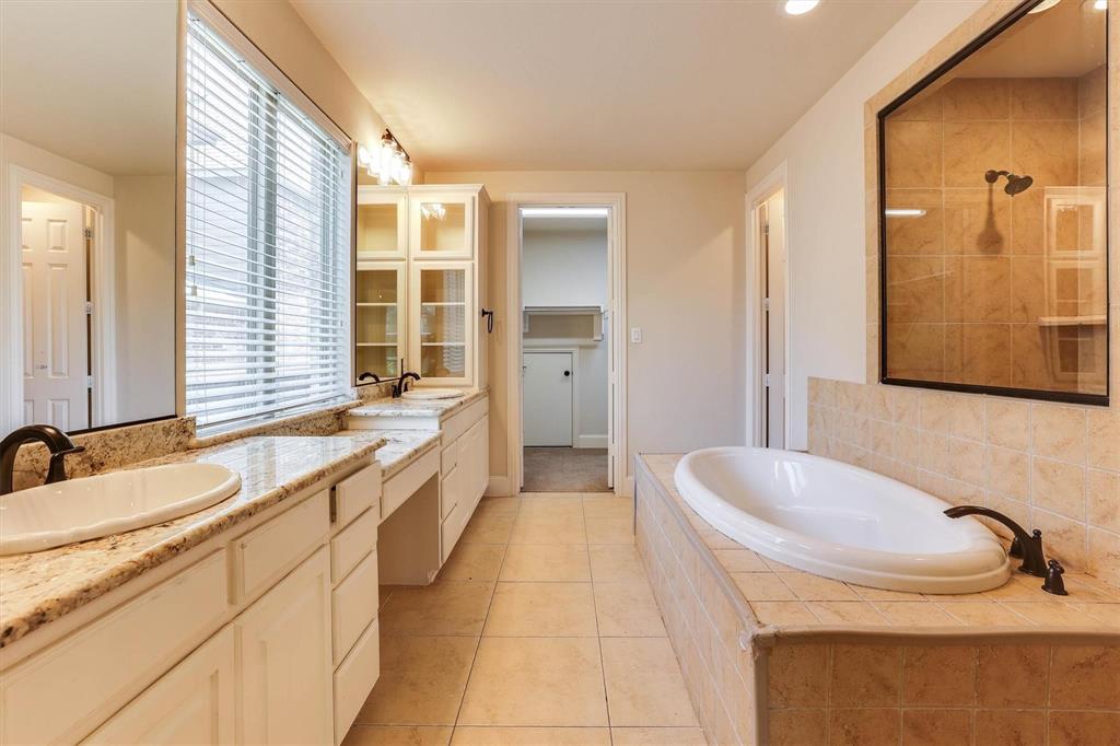 419 Rio Grande Drive Irving, TX 75039 - Photo 17 of 29 Spacious bathroom featuring a dual vanity with granite countertops, integrated drop-in sinks, and a built-in soaking tub