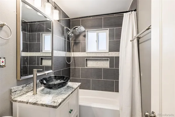 a bathroom with a granite countertop sink a mirror and shower