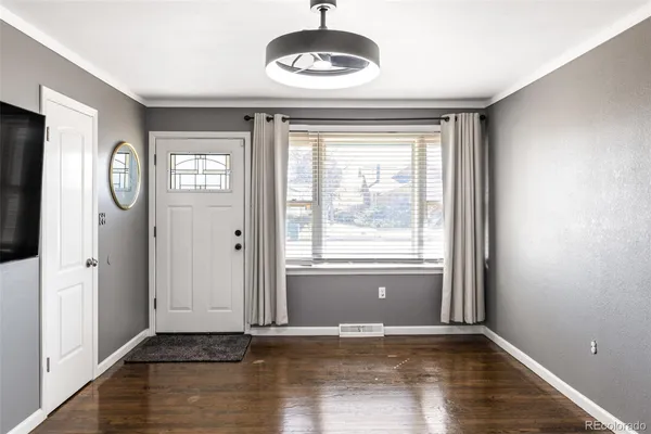 a view of an empty room with a window and wooden floor