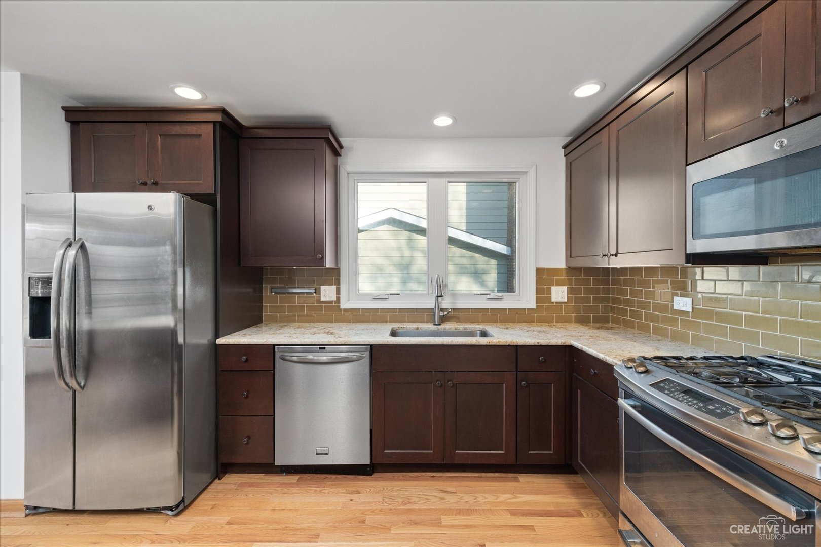 1925 Briarcliffe Boulevard Wheaton, IL 60189 - Photo 6 of 21 a kitchen with stainless steel appliances granite countertop a stove a sink dishwasher a refrigerator and cabinets with wooden floor