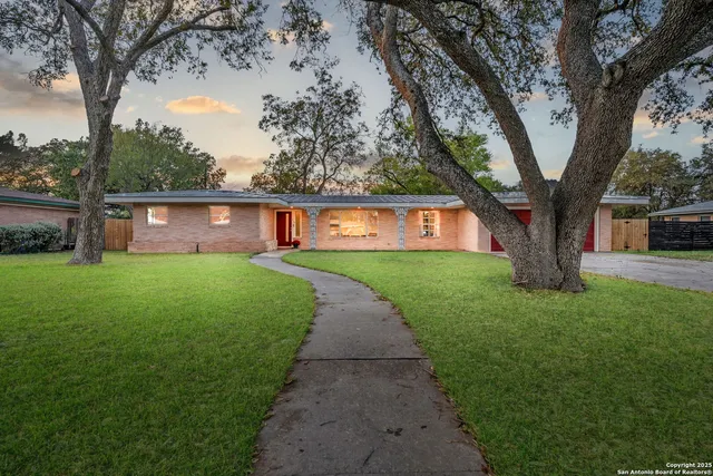 a view of house with a big yard and large trees