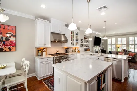 a kitchen with stainless steel appliances granite countertop a stove a sink a microwave oven a refrigerator a dining table and chairs with wooden floor